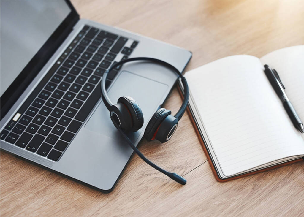 Laptop with headphones and notebook on table